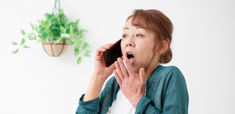 電話でシロアリの情報を聞いて驚く女性の写真
